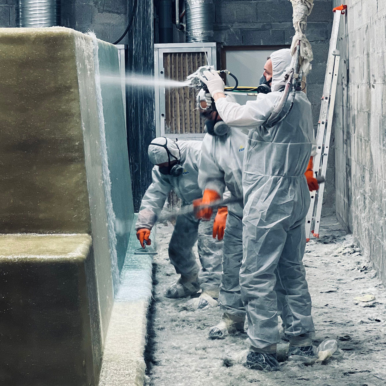 Fabrication de piscines en coque dans un environnement industriel avec des travailleurs en EPI utilisant des résines et gels, mettant en avant la sécurité, qualité des matériaux et travail d'équipe.