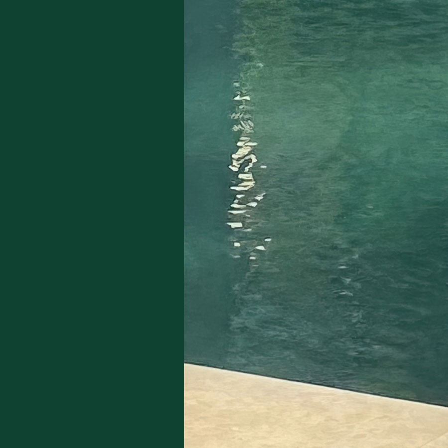Piscine coque avec eau vert bleuté, reflétant la lumière pour un effet esthétique, entourée d'un revêtement clair, symbole de facilité d'entretien et détente