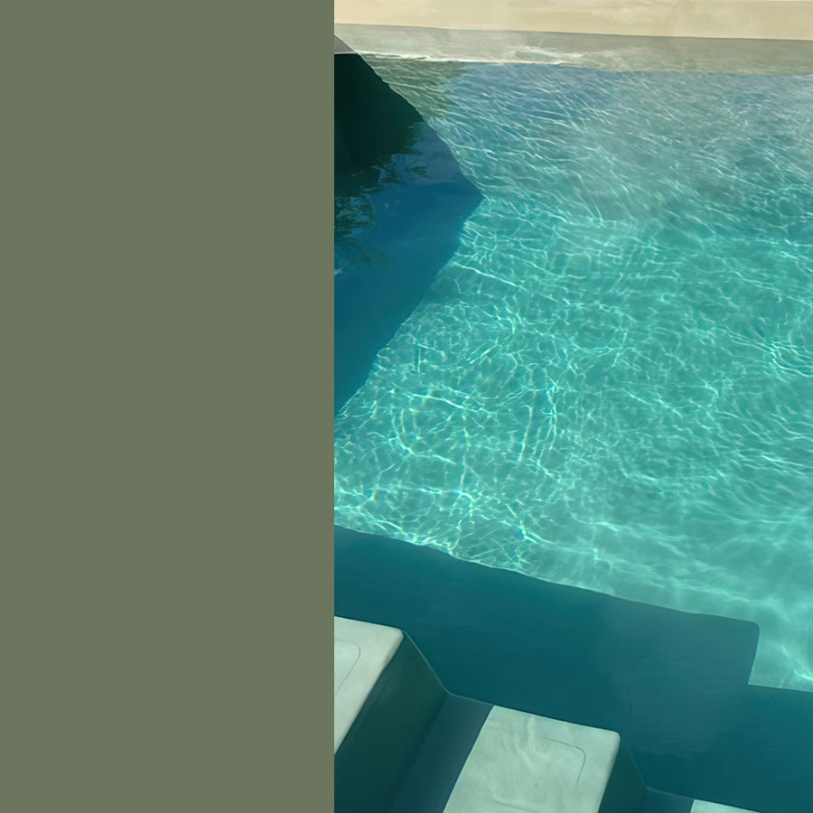 Piscine coque en fibre de verre turquoise avec éclairage nocturne intégré, entourée de pierres naturelles et de végétation, mettant en valeur la durabilité et l'esthétique élégante, idéale pour un jardin moderne et facile à entretenir.