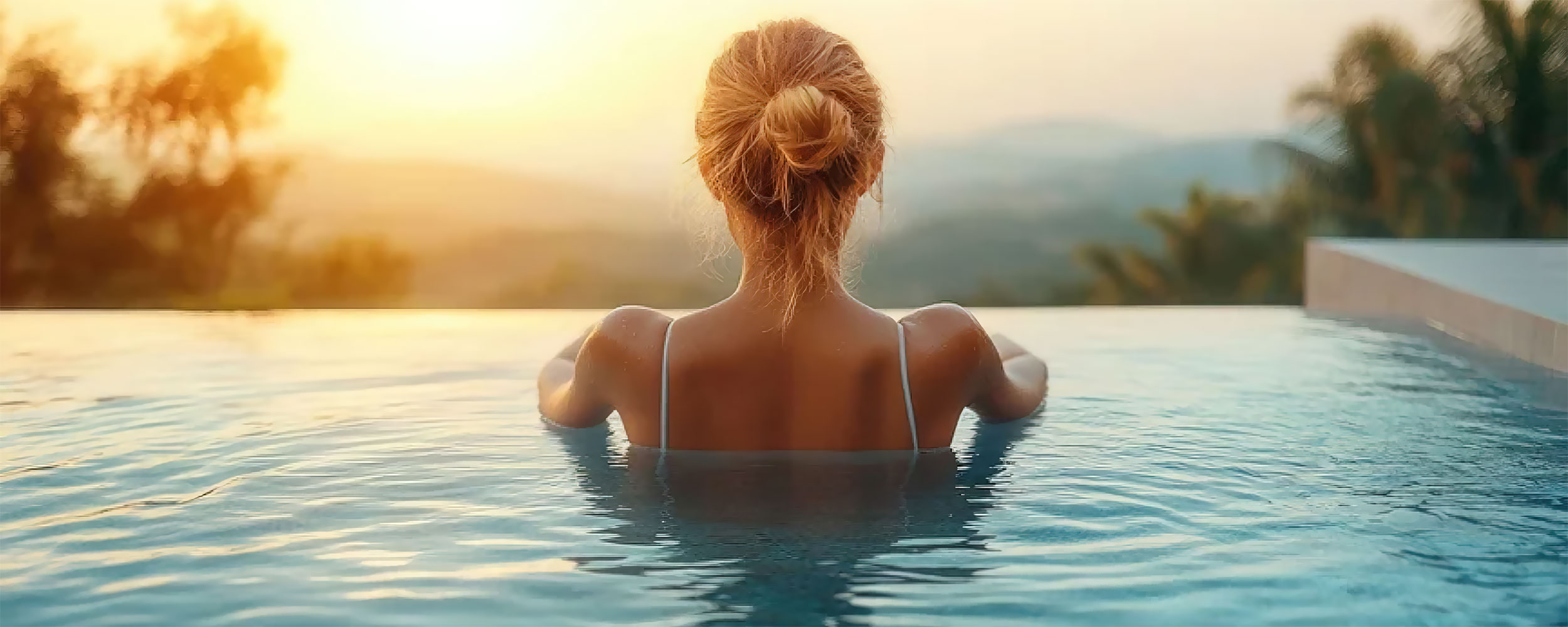 Piscine coque à débordement élégante au coucher de soleil, reflétant luxe et détente avec silhouette relaxante, montagnes et nature environnante