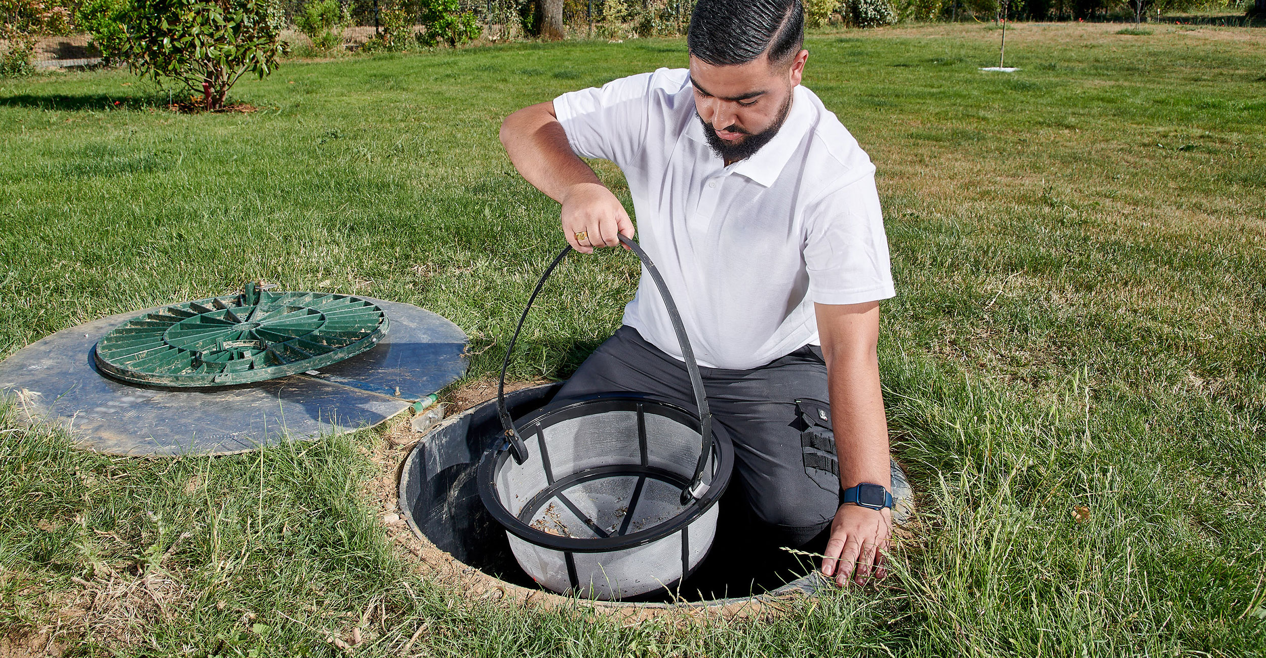 Professionnel en entretien piscine coque travaillant sur système de filtration dans jardin bien entretenu